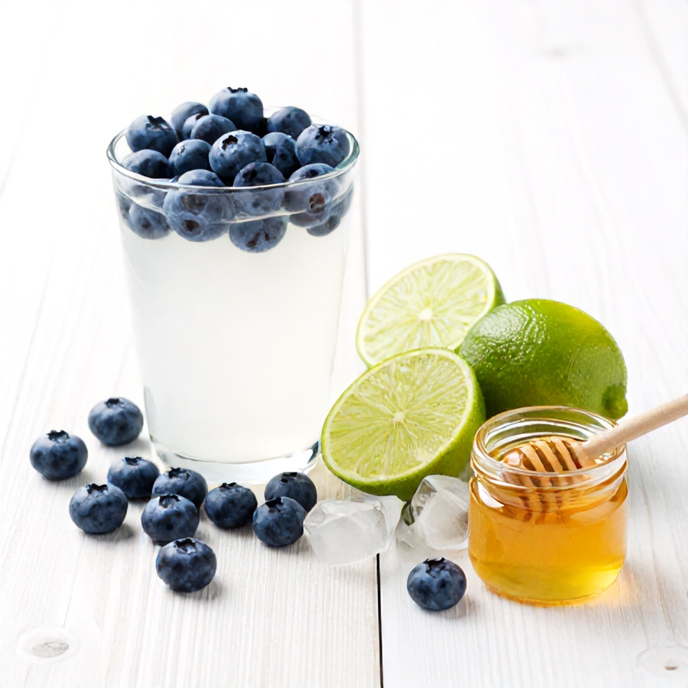 Blueberries, coconut water, lime, ice, and honey arranged on a wooden surface